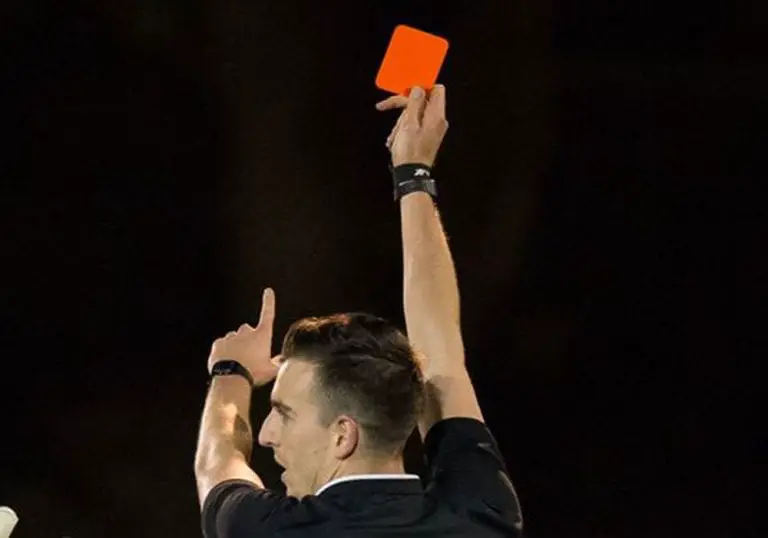 A referee brandishes a red card. Photo: Neil Graham.