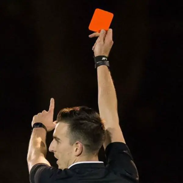 A referee brandishes a red card. Photo: Neil Graham.